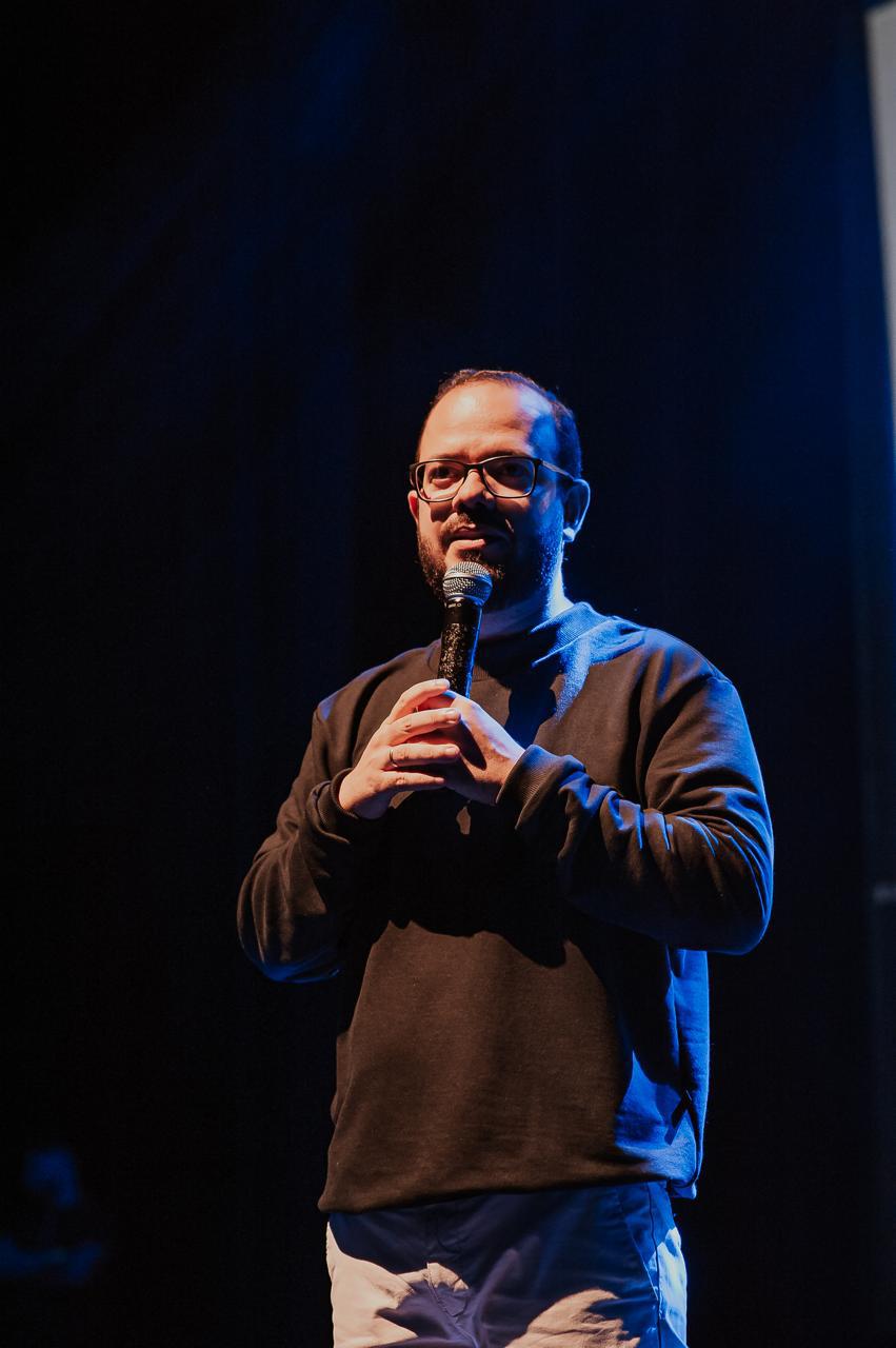 Tiago Lucena conduzindo apresentação em teatro