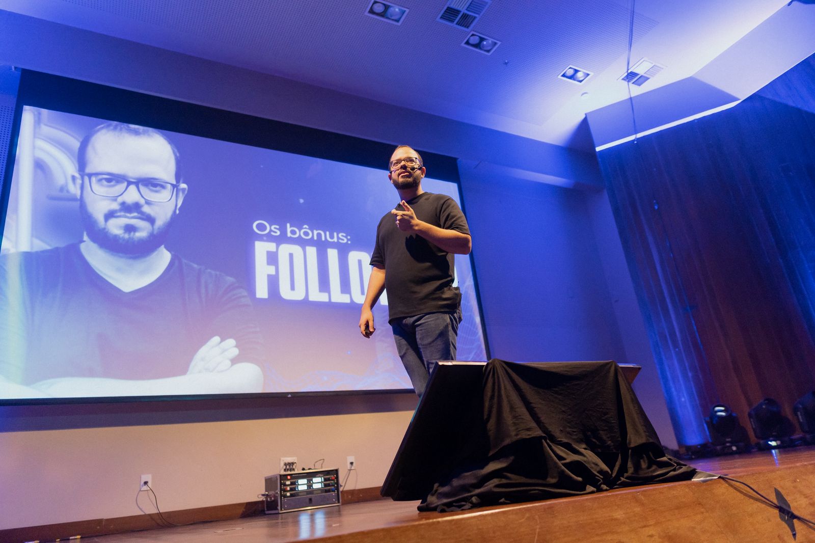 Tiago Lucena no palco com participante durante palestra